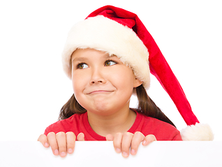 Image showing Little girl in santa hat is holding blank board