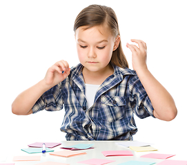 Image showing Girl is writing on color stickers using pen