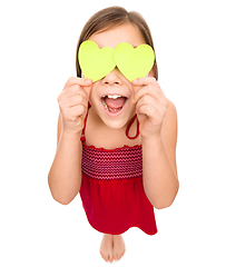 Image showing Little girl is holding hearts over her eyes