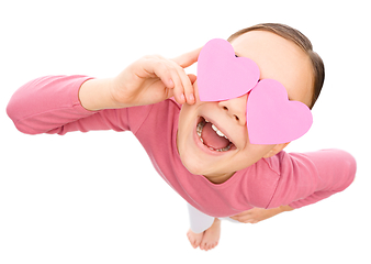 Image showing Little girl is holding hearts over her eyes