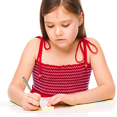 Image showing Girl is writing on color stickers using pen