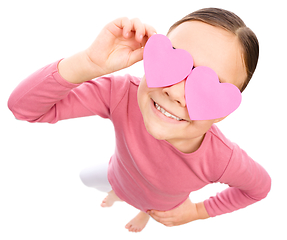 Image showing Little girl is holding hearts over her eyes