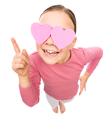 Image showing Little girl is holding hearts over her eyes