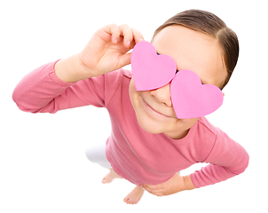 Image showing Little girl is holding hearts over her eyes