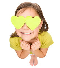 Image showing Little girl is holding hearts over her eyes