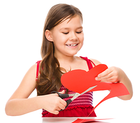 Image showing Portrait of a little girl cutting out red heart