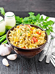 Image showing Barley porridge with minced meat in bowl on dark wooden board