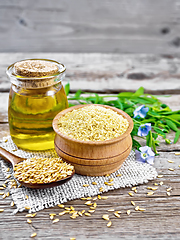 Image showing Bran flaxseed in bowl with oil in jar on board