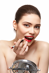 Image showing girl applying red lipstick isolated on white