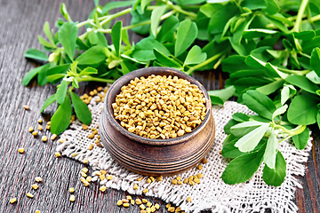 Image showing Fenugreek in bowl with leaves on dark wooden board