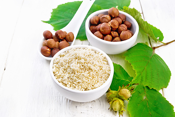 Image showing Flour and hazelnuts in bowls on white wooden board