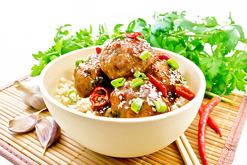 Image showing Meatballs in sweet and sour sauce with rice on wooden board