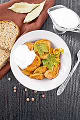 Image showing Mushrooms salted with sour cream in plate on dark board top