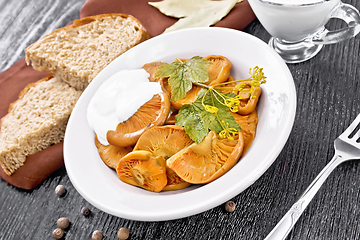 Image showing Mushrooms salted with sour cream in plate on wooden board