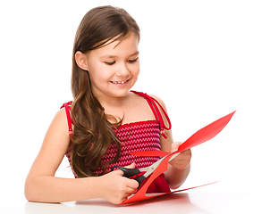 Image showing Portrait of a little girl cutting out red heart