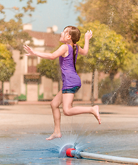 Image showing Girl is enjoying fountain with cold water