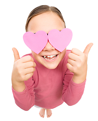 Image showing Little girl is holding hearts over her eyes