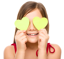 Image showing Little girl is holding hearts over her eyes