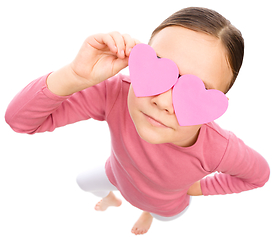 Image showing Little girl is holding hearts over her eyes