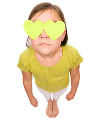 Image showing Little girl is holding hearts over her eyes