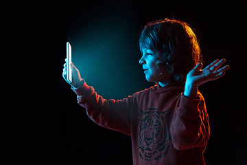 Image showing Caucasian boy\'s portrait isolated on dark studio background in neon light