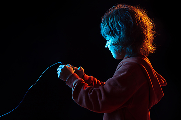 Image showing Caucasian boy\'s portrait isolated on dark studio background in neon light