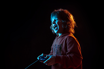 Image showing Caucasian boy\'s portrait isolated on dark studio background in neon light