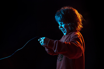 Image showing Caucasian boy\'s portrait isolated on dark studio background in neon light