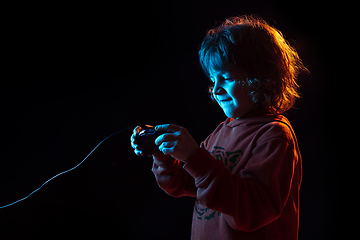 Image showing Caucasian boy\'s portrait isolated on dark studio background in neon light