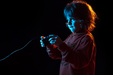 Image showing Caucasian boy\'s portrait isolated on dark studio background in neon light