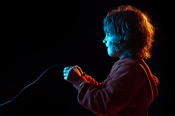 Image showing Caucasian boy\'s portrait isolated on dark studio background in neon light