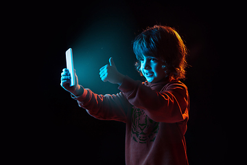 Image showing Caucasian boy\'s portrait isolated on dark studio background in neon light