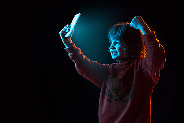 Image showing Caucasian boy\'s portrait isolated on dark studio background in neon light