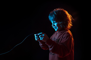 Image showing Caucasian boy\'s portrait isolated on dark studio background in neon light