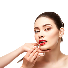 Image showing girl applying red lipstick isolated on white