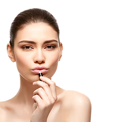 Image showing girl applying pink lipstick isolated on white