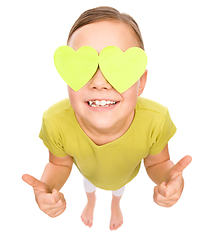 Image showing Little girl is holding hearts over her eyes