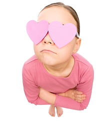 Image showing Little girl is holding hearts over her eyes