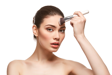 Image showing girl applying foundation on face isolated on white