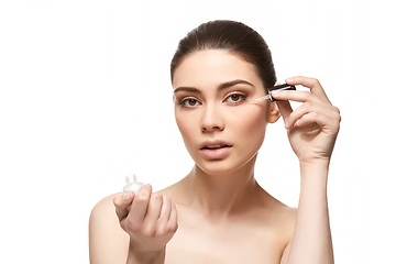 Image showing girl applying eye serum isolated on white