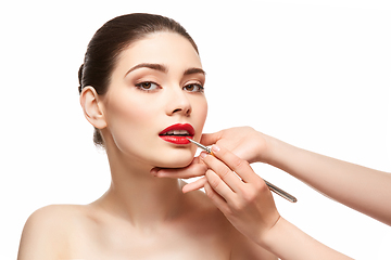 Image showing girl applying red lipstick isolated on white