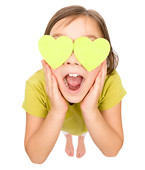 Image showing Little girl is holding hearts over her eyes