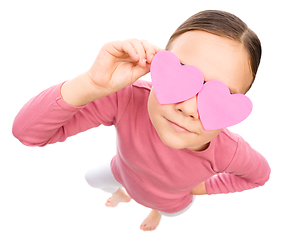 Image showing Little girl is holding hearts over her eyes