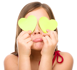 Image showing Little girl is holding hearts over her eyes