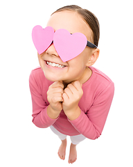 Image showing Little girl is holding hearts over her eyes