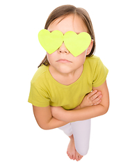 Image showing Little girl is holding hearts over her eyes