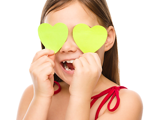 Image showing Little girl is holding hearts over her eyes