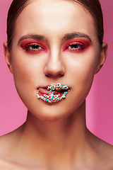 Image showing beautiful girl with candies on pink backgroound