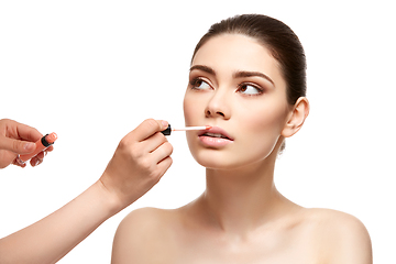 Image showing girl applying pink lipstick isolated on white