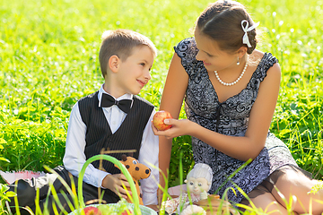 Image showing Little boy and teen age girl having picnic outdoors